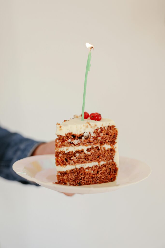 pexels-photo-8014704-8014704 Slice of cake with lit candle on a plate, perfect for celebrations.